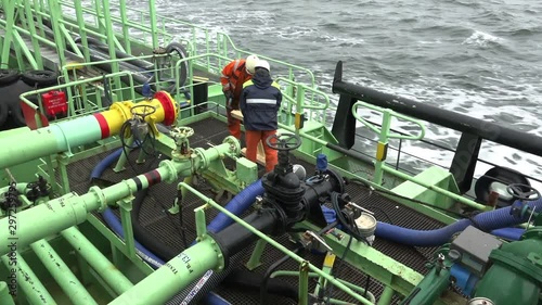 oil tanker Onyx ship workers repair wooden scaffolding among long pipes on deck against gale sea water
