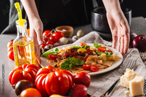 Italian traditional cuisine. Plate of delicious pasta with tomatoes on the kitchen table. Close-up.