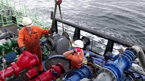 skilled motorman-pump and sailor connect fuel pump meter to pipeline for pumping fuel oil from tanker to bunkered vessels photo