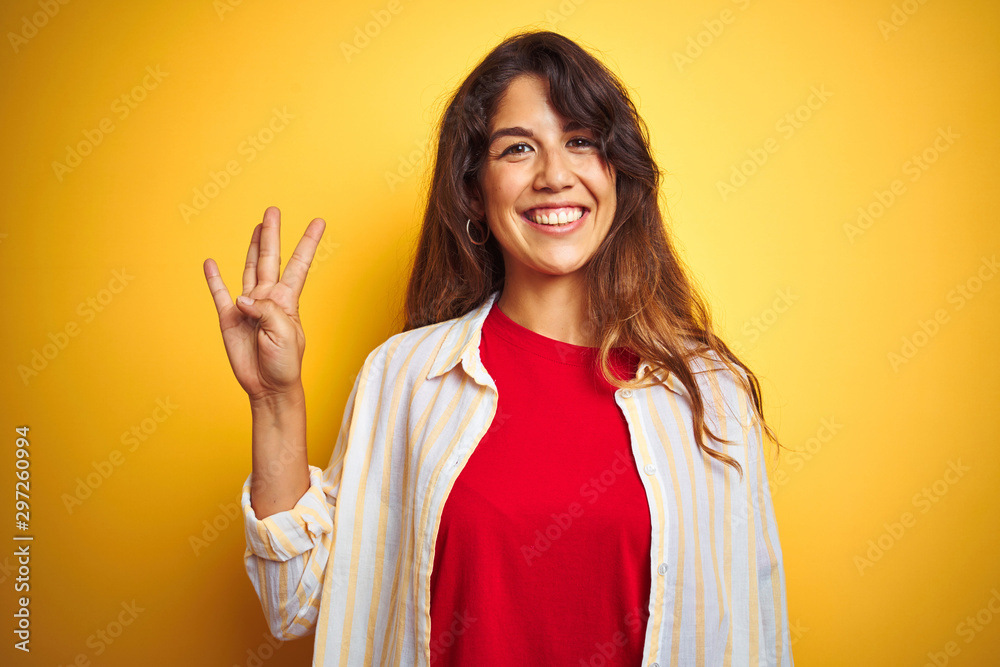 Young beautiful woman wearing red t-shirt and stripes shirt over yellow isolated background showing and pointing up with fingers number four while smiling confident and happy. Young beautiful woman wearing red t-shirt and stripes shirt over yellow isolated background showing and pointing up with fingers number four while smiling confident and happy.