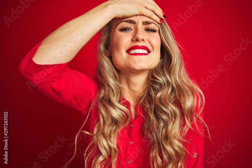 Young beautiful woman standing over red isolated background stressed with hand on head, shocked with shame and surprise face, angry and frustrated. Fear and upset for mistake.