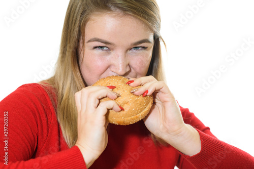 Young fat girl on a white background eats a burger. Studio shot