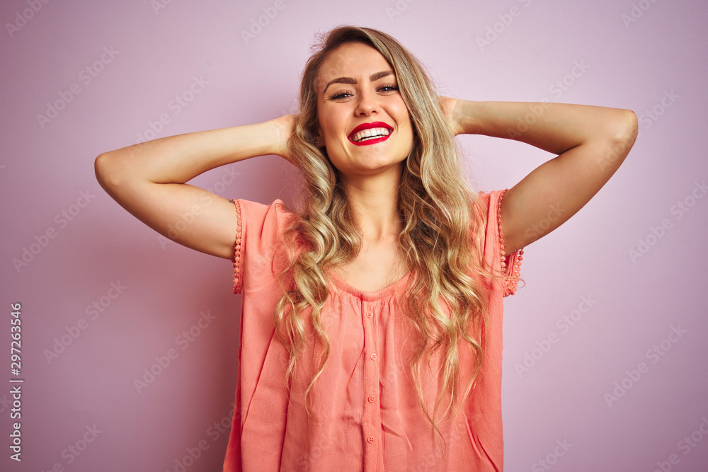 Young beautiful woman wearing t-shirt standing over pink isolated background relaxing and stretching, arms and hands behind head and neck smiling happy Young beautiful woman wearing t-shirt standing over pink isolated background relaxing and stretching, arms and hands behind head and neck smiling happy