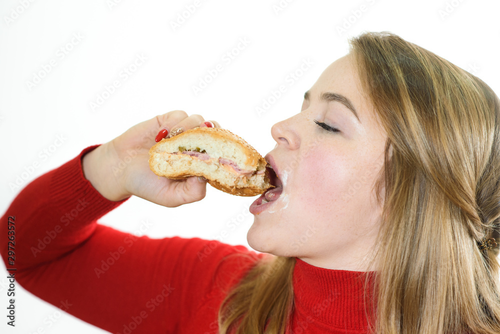 Young fat girl on a white background eats a burger. Studio shot Young fat girl on a white background eats a burger. Studio shot