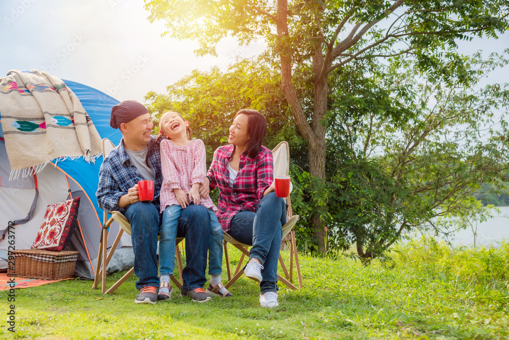 Obraz premium Group of asian family travel and camping at lakeside in forest ,sitting all together and smile. Family and outdoor activity concept.