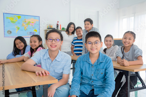 Many male and female students Sitting in the classroom with a teacher And turned to smile at the camera,Education concept.