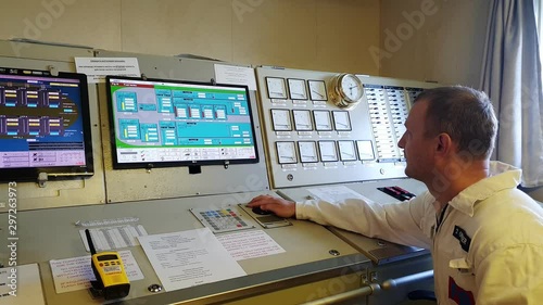 serious man in white shirt looks at scheme on display and analyses information at vessel control panel closeup