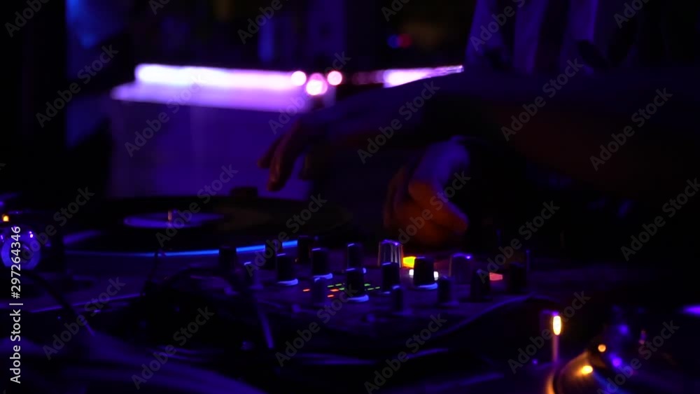 Close up of DJ using the vinyl player at the party, bright purple lighting