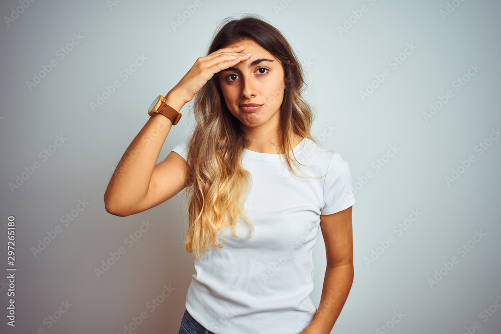 Young beautiful woman wearing casual white t-shirt over isolated background worried and stressed about a problem with hand on forehead, nervous and anxious for crisis