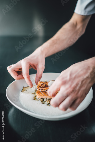 Restaurant chef preparing fish food on dark table. Organic fish food