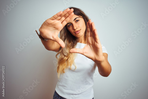 Young beautiful woman wearing casual white t-shirt over isolated background doing frame using hands palms and fingers, camera perspective photo
