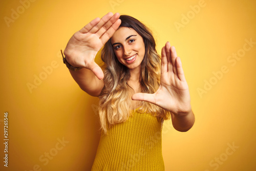 Young beautiful woman wearing t-shirt over yellow isolated background doing frame using hands palms and fingers, camera perspective