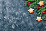 Christmas and New Year background with winter berries, ginger cookies in the form of a star and fir branches in a dark style. Copy space and top view.