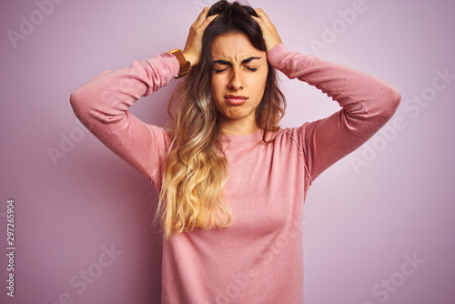Young beautiful woman wearing a sweater over pink isolated background suffering from headache desperate and stressed because pain and migraine. Hands on head.
