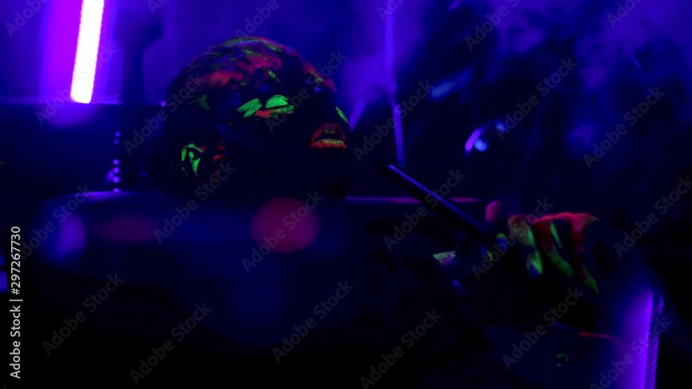 lady with fluorescent imprint on face smokes hookah