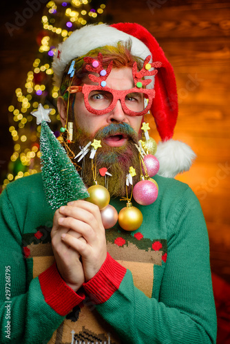 Santa Claus hold tree. New year clothes. New Year eve. Santa in home. Santa Claus. Merry Christmas and happy New year. Wish you merry Christmas. Present box. Gift.