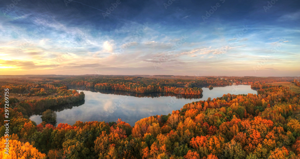 Amazing sunset over the autumnal forest and lake in Poland