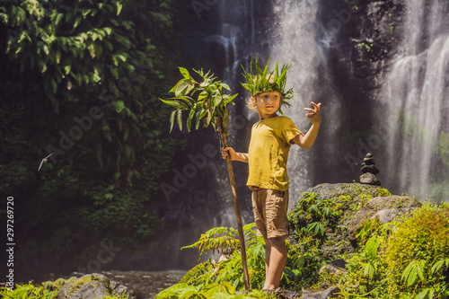Cute boy depicts the king of the jungle against the backdrop of a waterfall. Childhood without gadgets concept. Traveling with children concept. Childhood outdoors concept