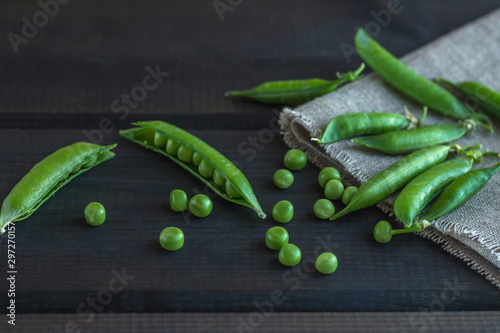 Pods of green peas and pea on a dark wooden surface. The concept of vegetarian food. Organic foods and fresh vegetables.
