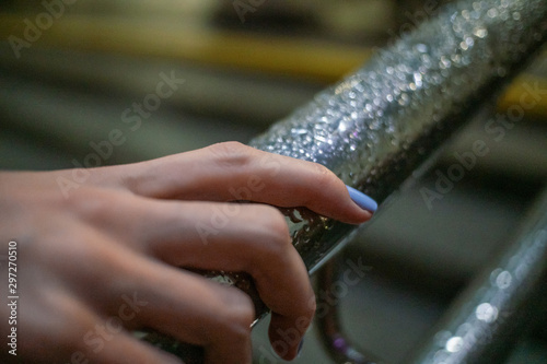 Close up of a girl s hands on an iron railing with raindrops in the evening