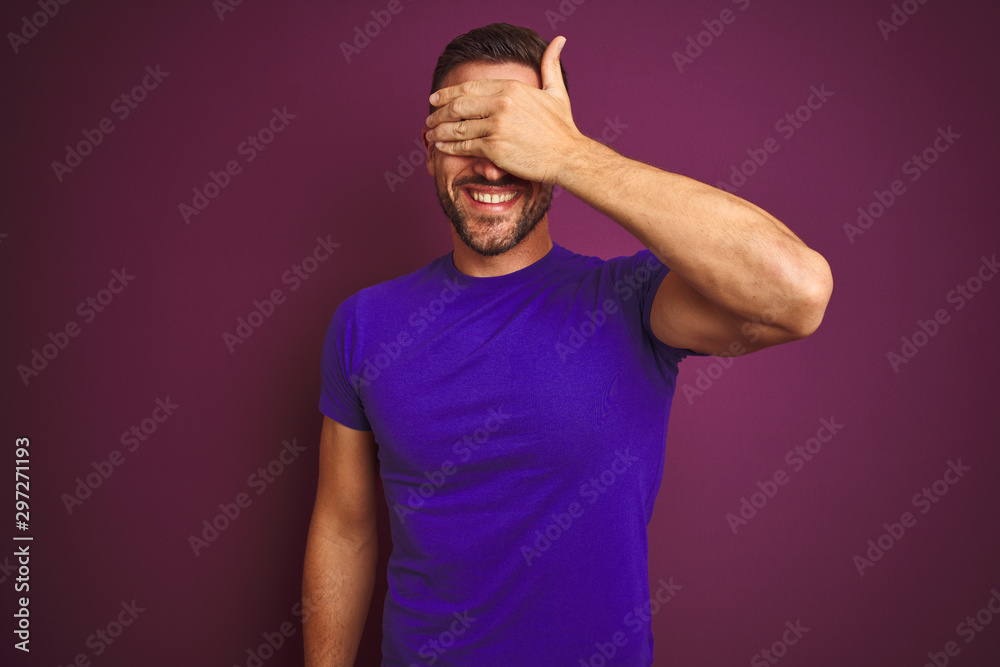 Young man wearing casual purple t-shirt over lilac isolated background smiling and laughing with hand on face covering eyes for surprise. Blind concept. Young man wearing casual purple t-shirt over lilac isolated background smiling and laughing with hand on face covering eyes for surprise. Blind concept.