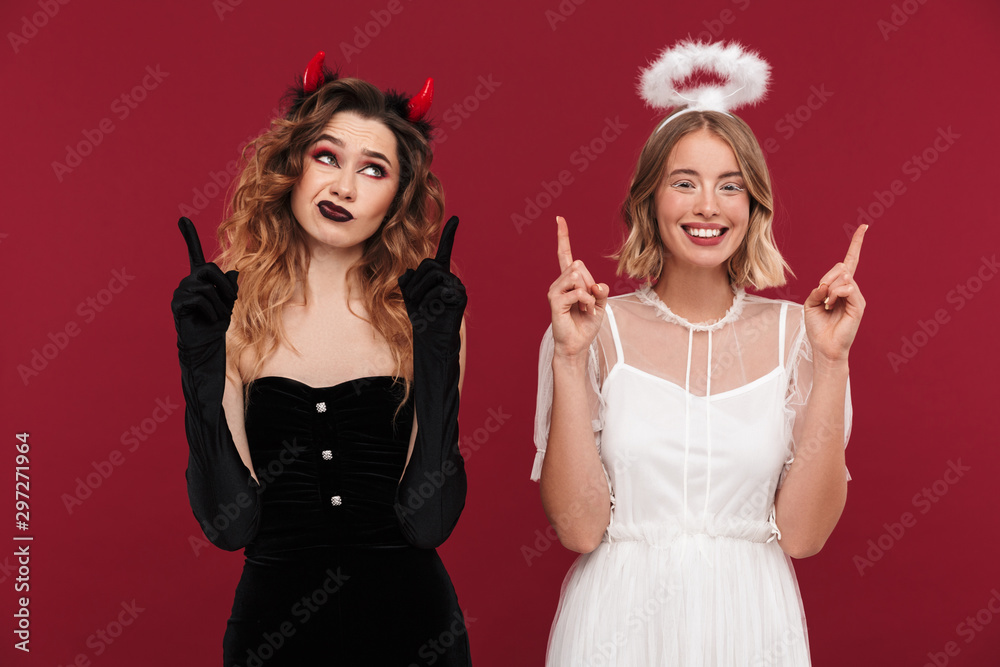 Demon and positive angel in carnival costumes pointing aside. Demon and positive angel in carnival costumes pointing aside.