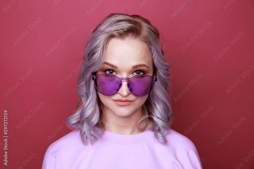 Portrait of young woman in bright glasses standing isolated over the pink background Portrait of young woman in bright glasses standing isolated over the pink background