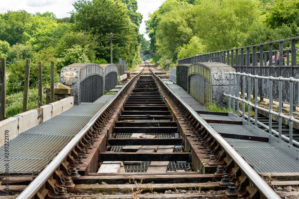 Detailed, low level view of a railway track seen spanning a wrought Iron bridge in the English Countryside. Detail of the tracks and Iron bridge are visible. Detailed, low level view of a railway track seen spanning a wrought Iron bridge in the English Countryside. Detail of the tracks and Iron bridge are visible.