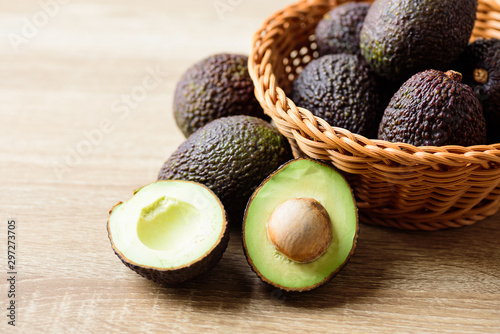 Ripe hass avocado fruit in basket on wooden background photo