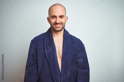 Young man wearing blue bathrobe, relaxed lifestyle over isolated background with a happy and cool smile on face. Lucky person.