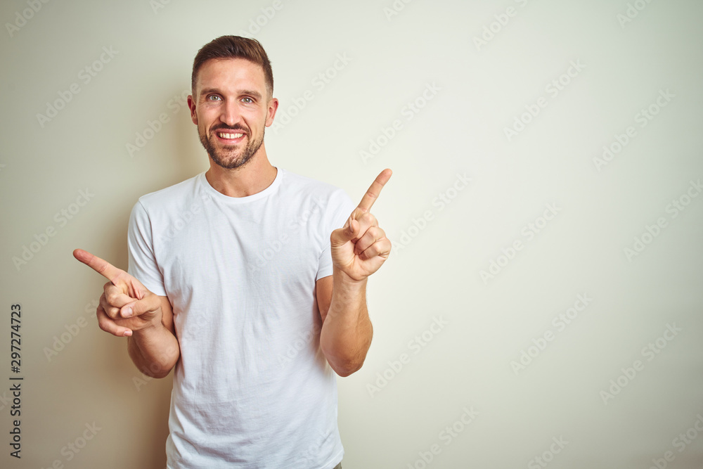 Young handsome man wearing casual white t-shirt over isolated background smiling confident pointing with fingers to different directions. Copy space for advertisement Young handsome man wearing casual white t-shirt over isolated background smiling confident pointing with fingers to different directions. Copy space for advertisement