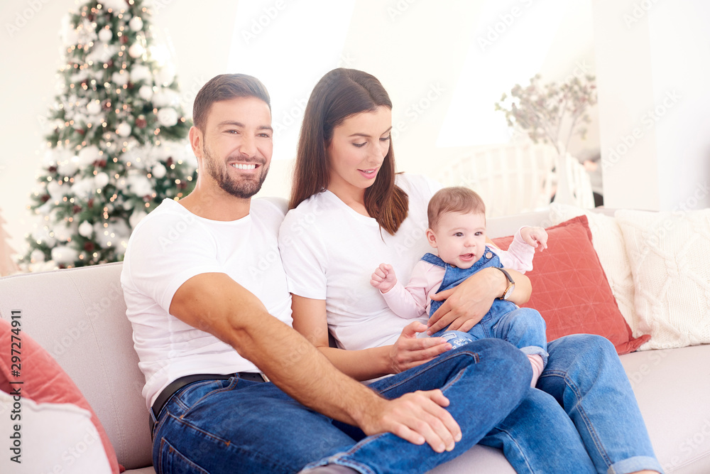 Lovely family with their baby girls relaxing on sofa at home