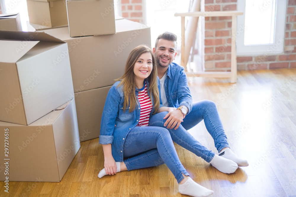 Young beautiful couple in love moving to new home, sitting on the floor very happy and cheerful for new apartment around cardboard boxes Young beautiful couple in love moving to new home, sitting on the floor very happy and cheerful for new apartment around cardboard boxes