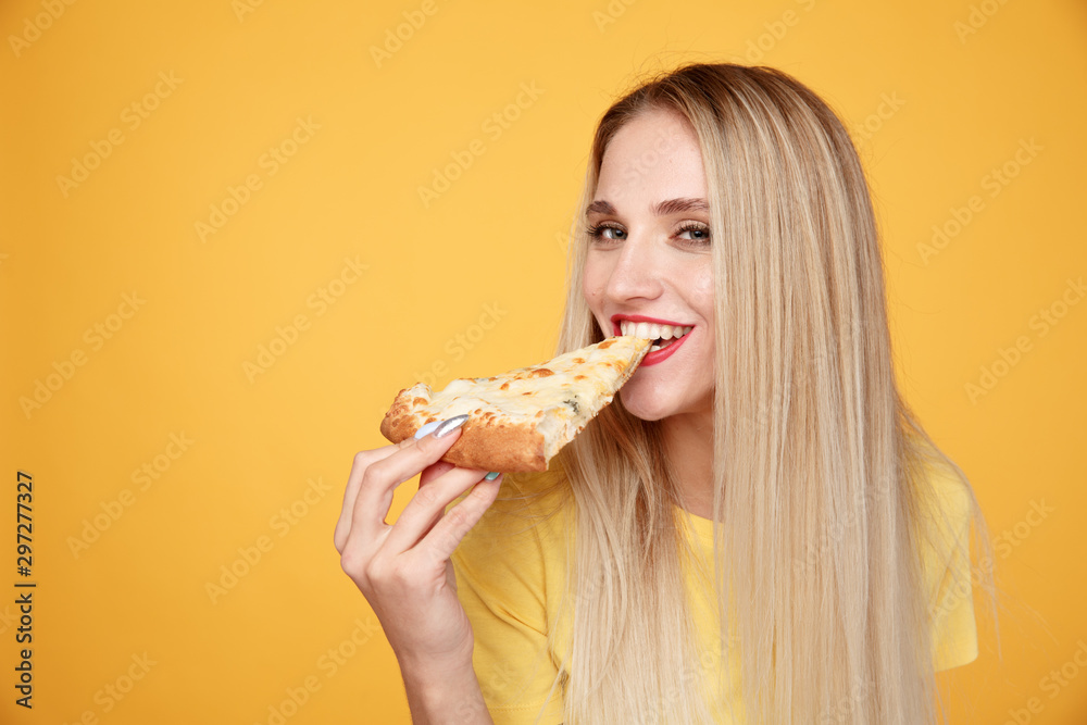 Happy woman eating tasty pizza for lunch in the yellow studio Happy woman eating tasty pizza for lunch in the yellow studio