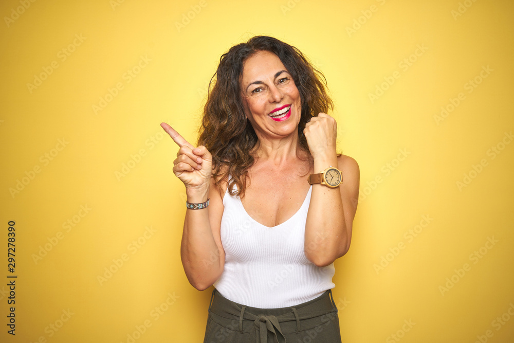 Middle age senior woman showing wrist watch over yellow isolated background very happy pointing with hand and finger to the side Middle age senior woman showing wrist watch over yellow isolated background very happy pointing with hand and finger to the side