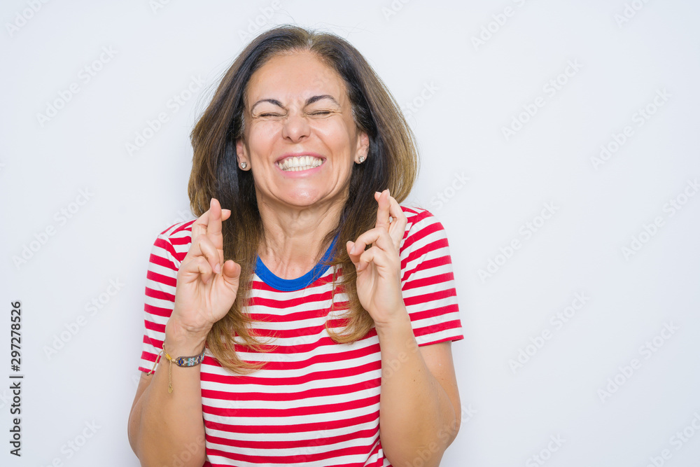 Middle age senior woman standing over white isolated background gesturing finger crossed smiling with hope and eyes closed. Luck and superstitious concept. Middle age senior woman standing over white isolated background gesturing finger crossed smiling with hope and eyes closed. Luck and superstitious concept.