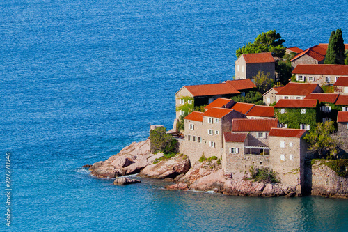 houses covered with red tiles and bright blue sea close-up Montenegro, Sveti Stefan.