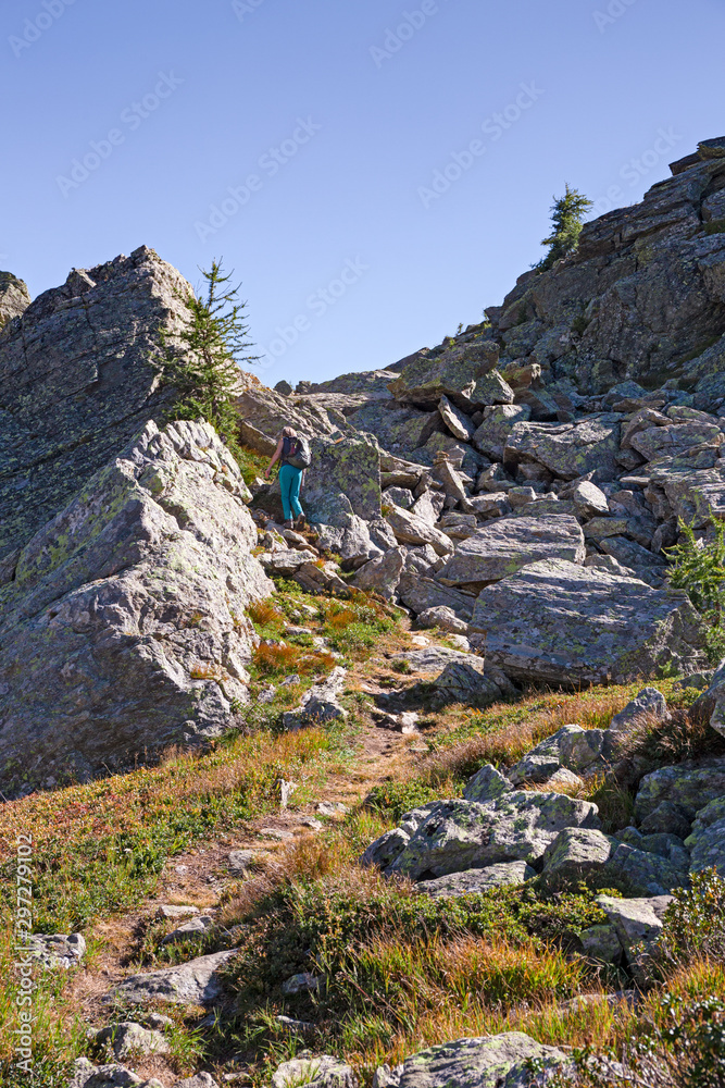 A hiker walking on the mountain path on a sunny autumn day.