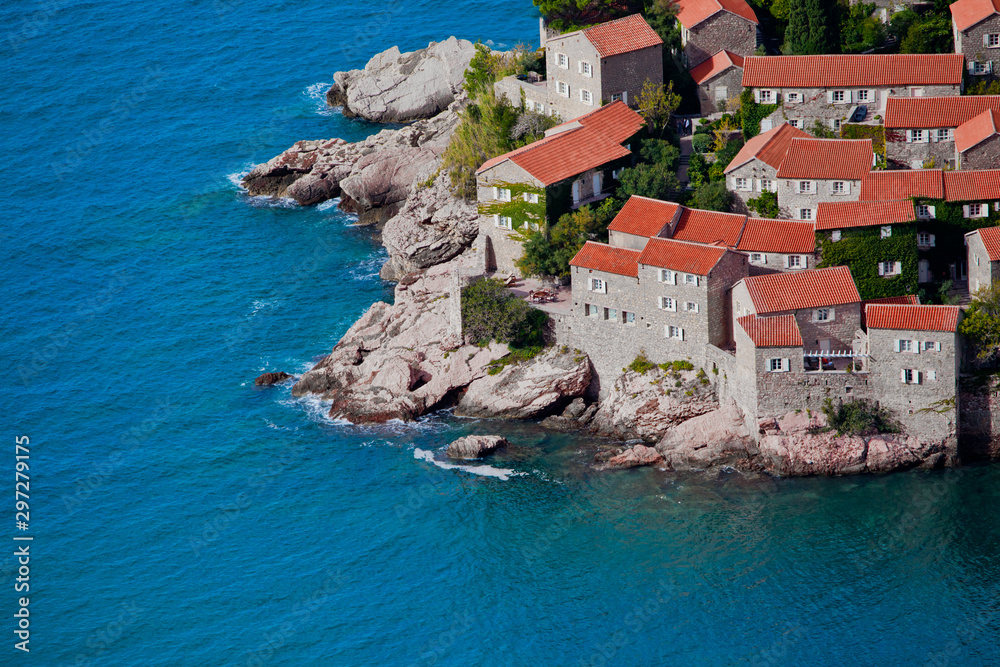 houses covered with red tiles and bright blue sea close-up Montenegro, Sveti Stefan.