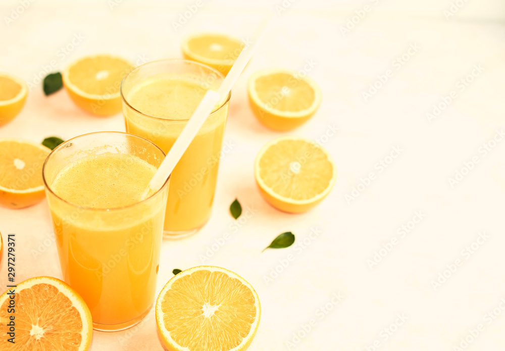 fresh orange in a glass with a straw on a neutral background with cut oranges on the table fresh orange in a glass with a straw on a neutral background with cut oranges on the table