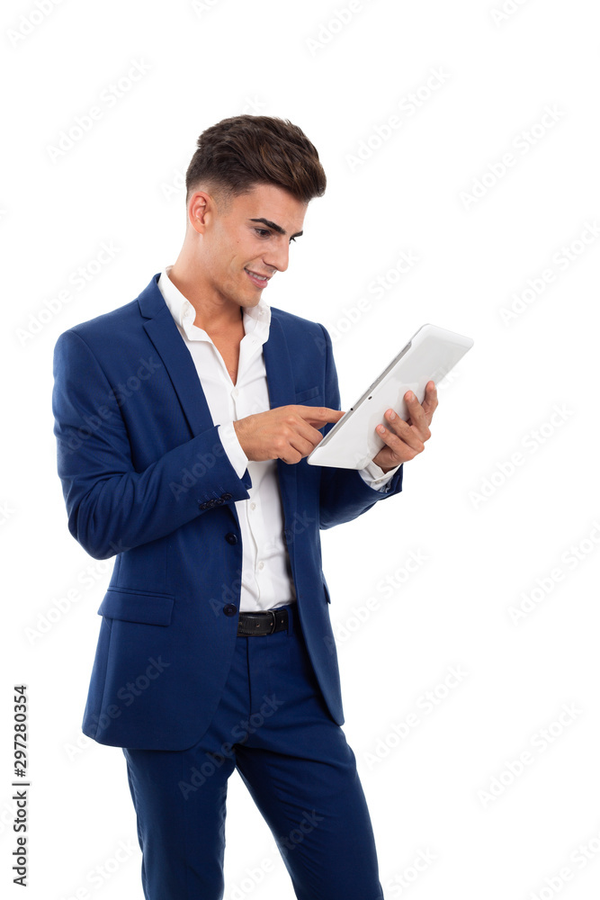 young smiling businessman using a white tablet mobile. He is wearing a blue jacket suit and a white shirt. He is in a photo studio.
