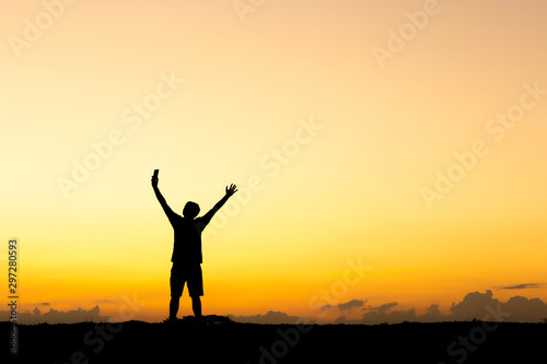Silhouette of man standing enjoying with smartphone sunset / sunrise evening sky background, Happiness and active life Concept.