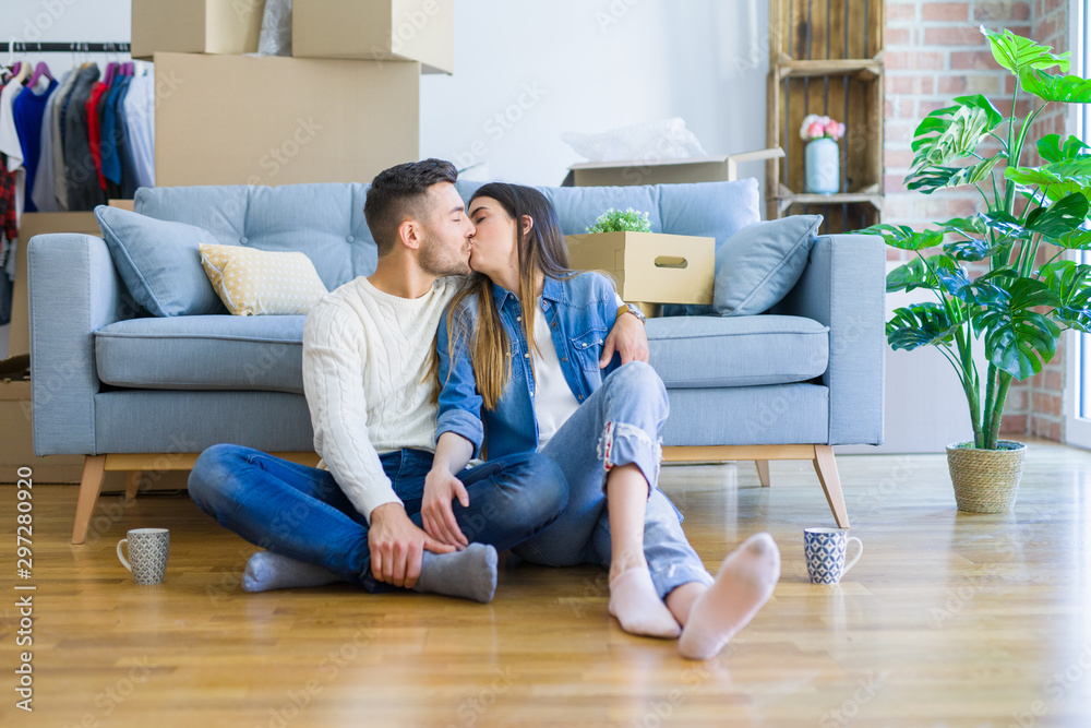 Young beautiful couple sitting on the floor of new apartment, smiling in love happy for moving to a new home Young beautiful couple sitting on the floor of new apartment, smiling in love happy for moving to a new home