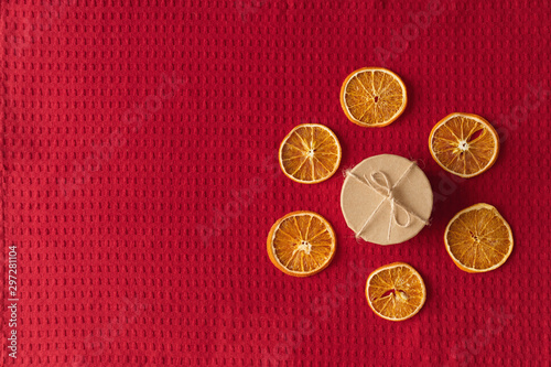 Craft box and dried oranges on a red background with copy space. Healthy sweets and christmas concept. Flat lay