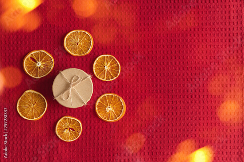 Craft box and dried oranges on a red background with christmas lights and copy space. Healthy sweets concept. Flat lay