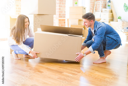 Beautiful young couple smiling in love holding a big cardboard box, happy for moving to a new home © Krakenimages.com