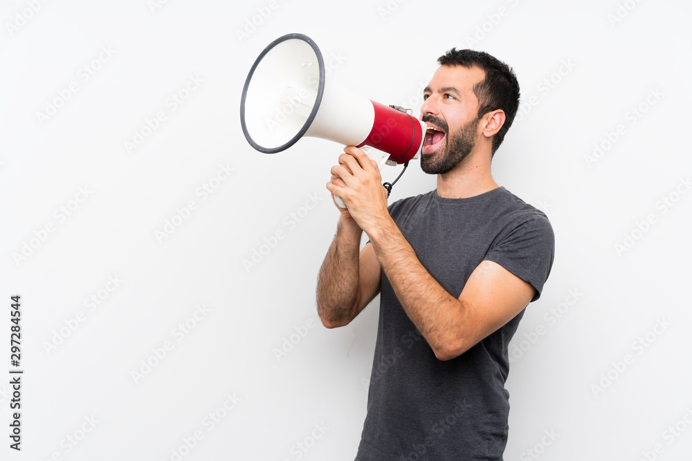Young handsome man over isolated white background shouting through a megaphone Young handsome man over isolated white background shouting through a megaphone
