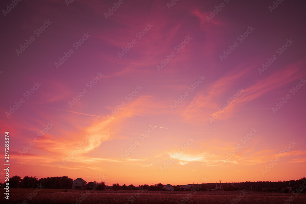 Rural landscape in the evening in sunset light.  Silhouette of the village on the horizon