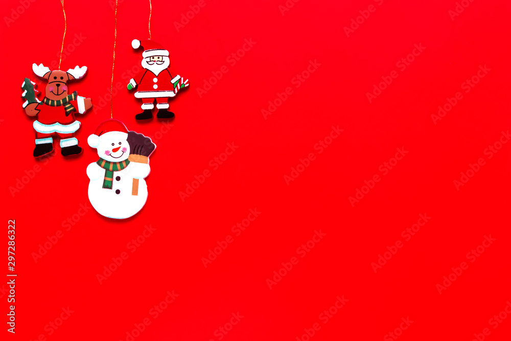 Fototapeta premium Wooden christmas decorations Santa, snowman and deer on red background. Merry Christmas and Happy New Year concept. Top view, flat lay, copy space.