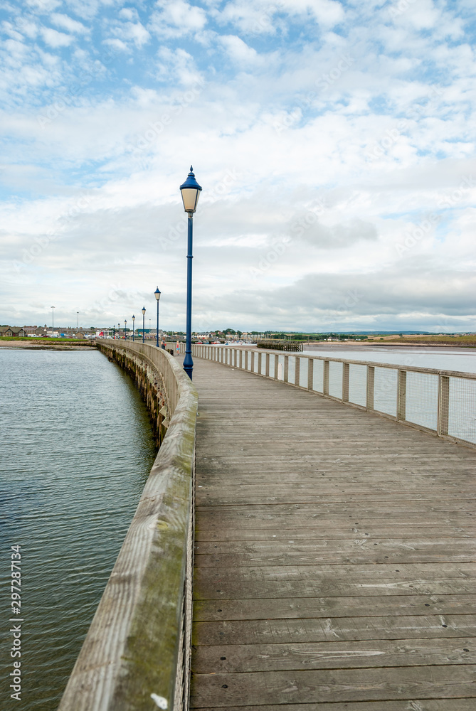 View towards the shore along an old English wooden jetty lined with street lamps
